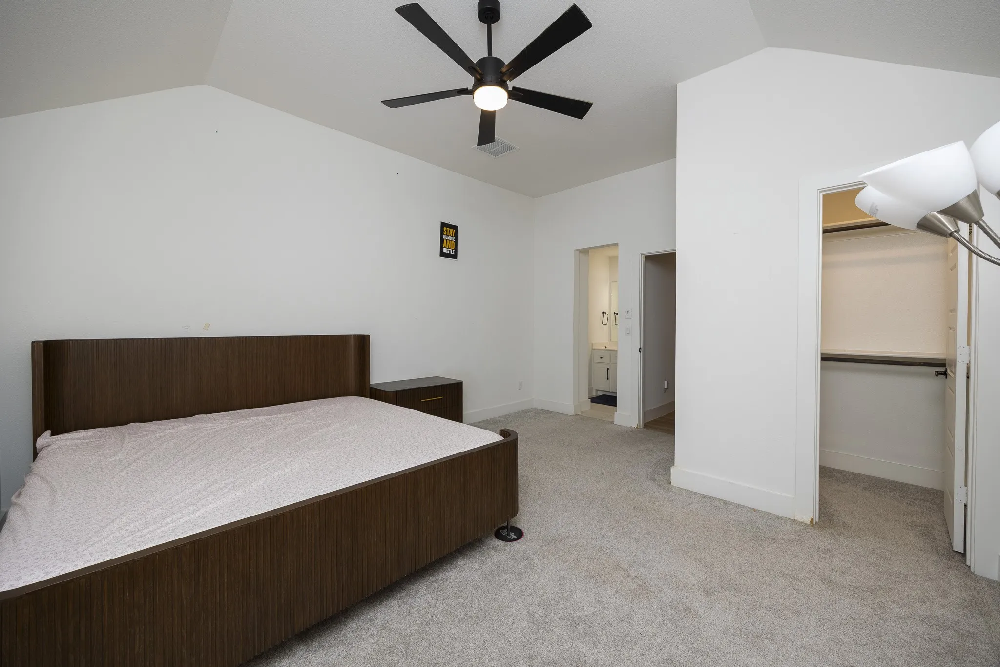 Vaulted ceiling with a ceiling fan, light gray carpet, and an open closet