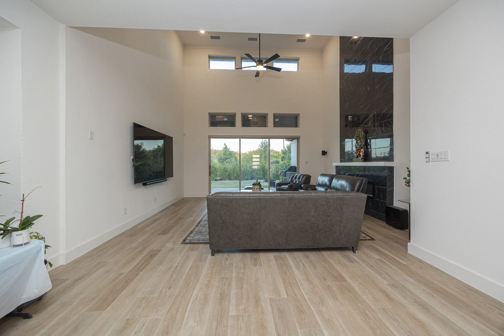 Vaulted ceilings with recessed lighting, large format wood-finish flooring, and a fireplace with a dark stone surround