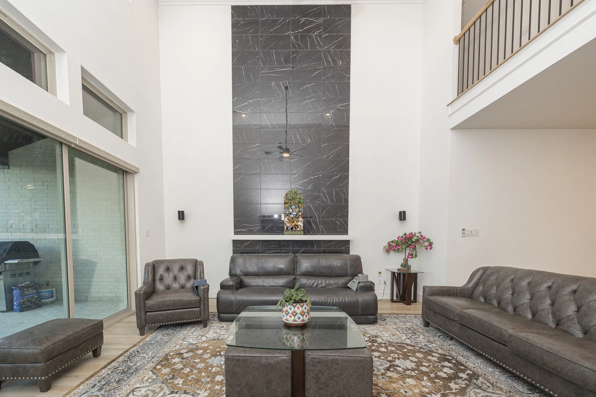 Vaulted ceiling with transom windows, full-height black and white veined accent wall, and wood-finish flooring