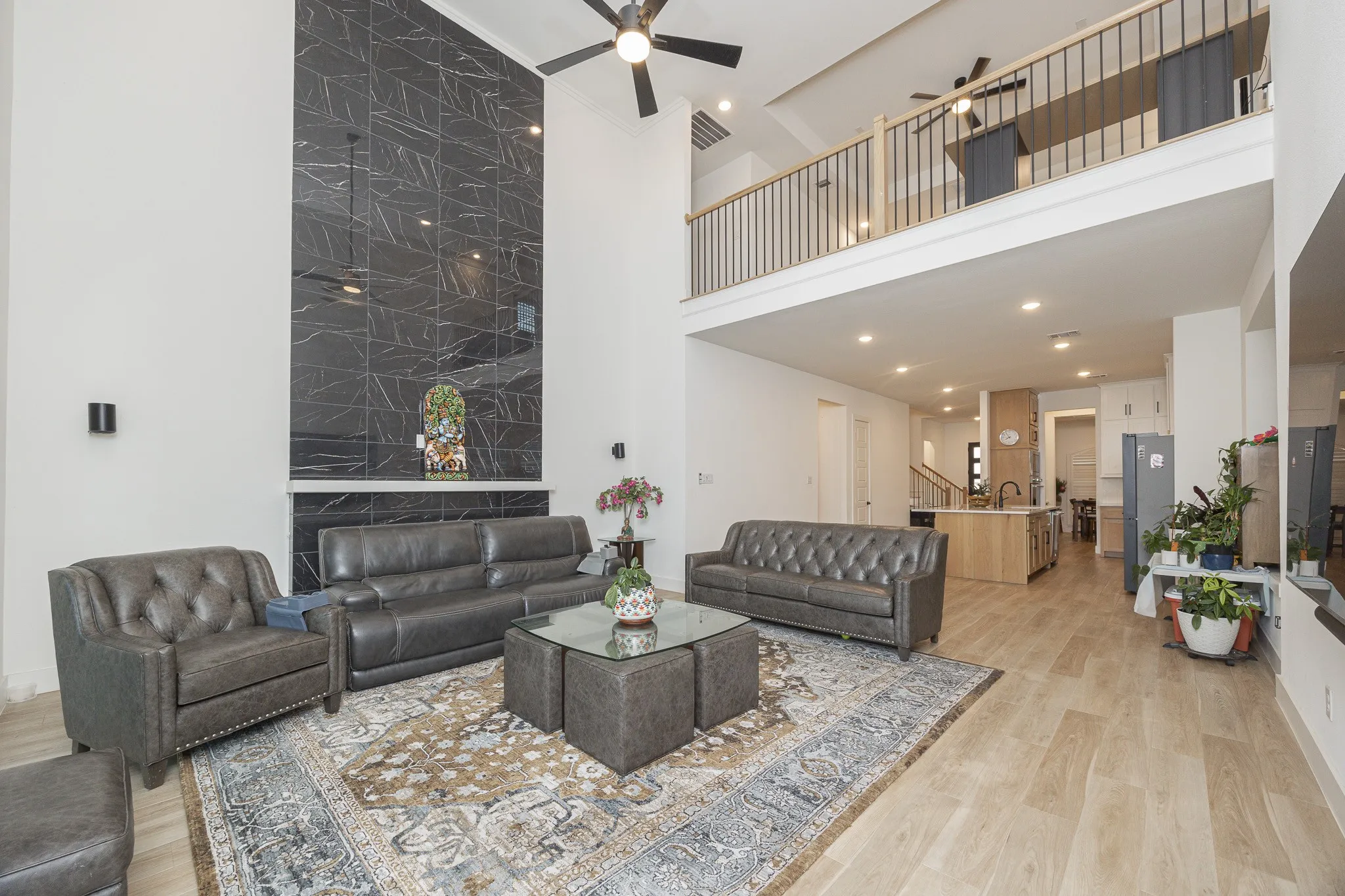 Two-story living area with high ceilings, featuring a floor-to-ceiling tiled fireplace and an open loft