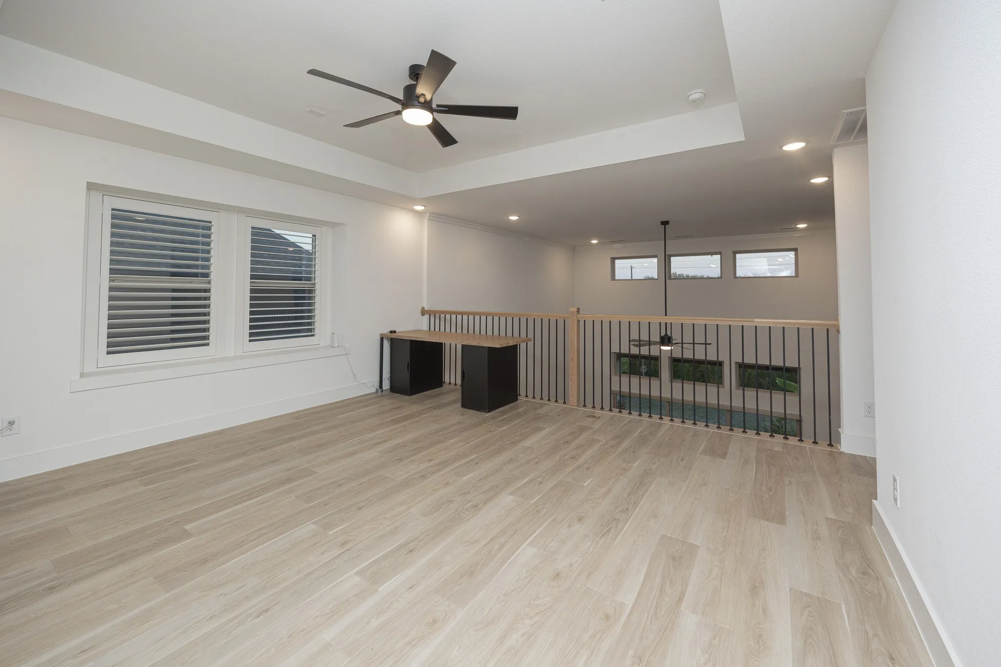 Spacious room featuring wood-finish flooring, a contemporary ceiling fan, and a built-in desk