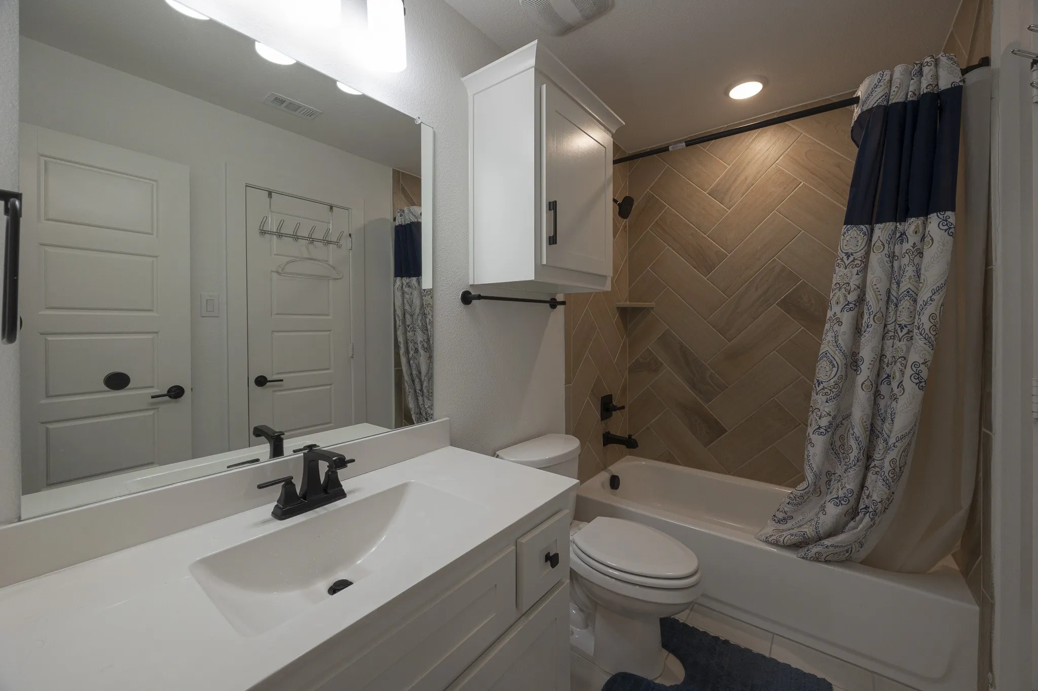Bathroom featuring a white vanity with an integrated sink, black faucet, and a large mirror