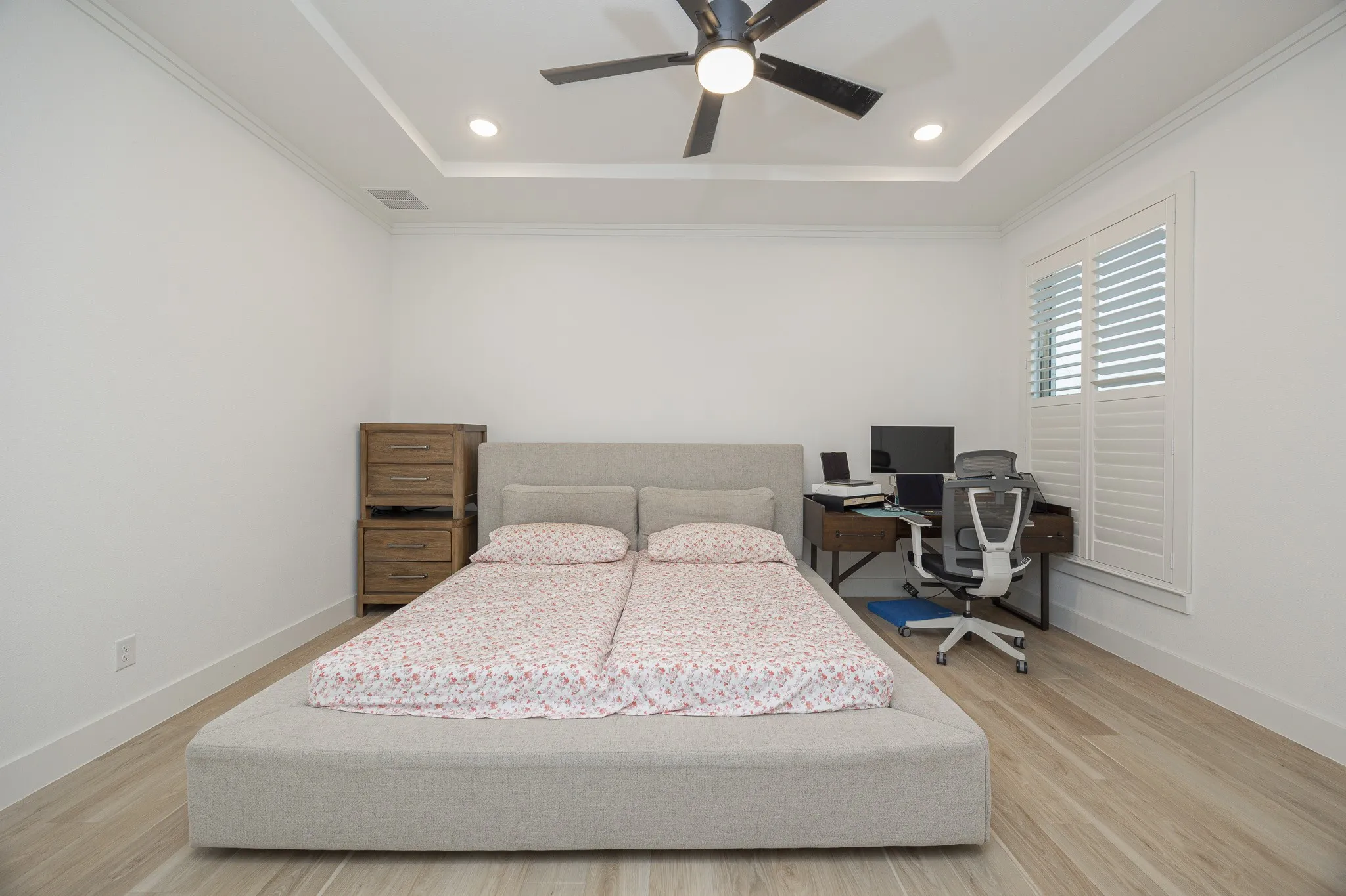 Tray ceiling with recessed lighting, wood-finish flooring, and crown molding