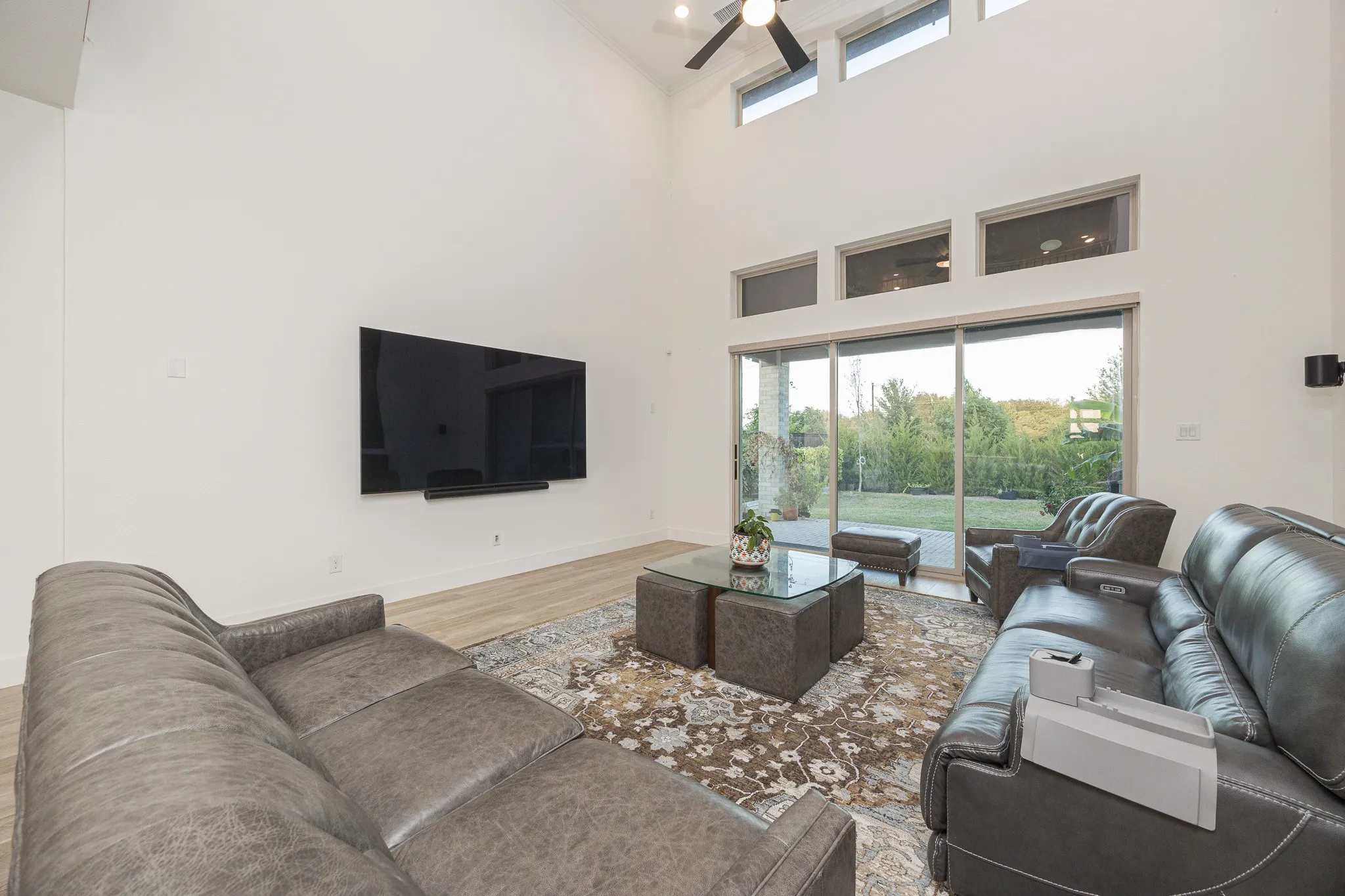 Vaulted ceiling with a ceiling fan, wood-finish flooring, and expansive sliding glass doors