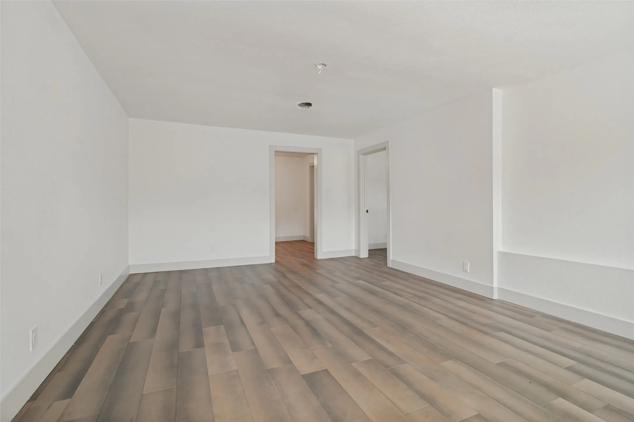 Wood-finish flooring throughout, bright white walls, and open doorways