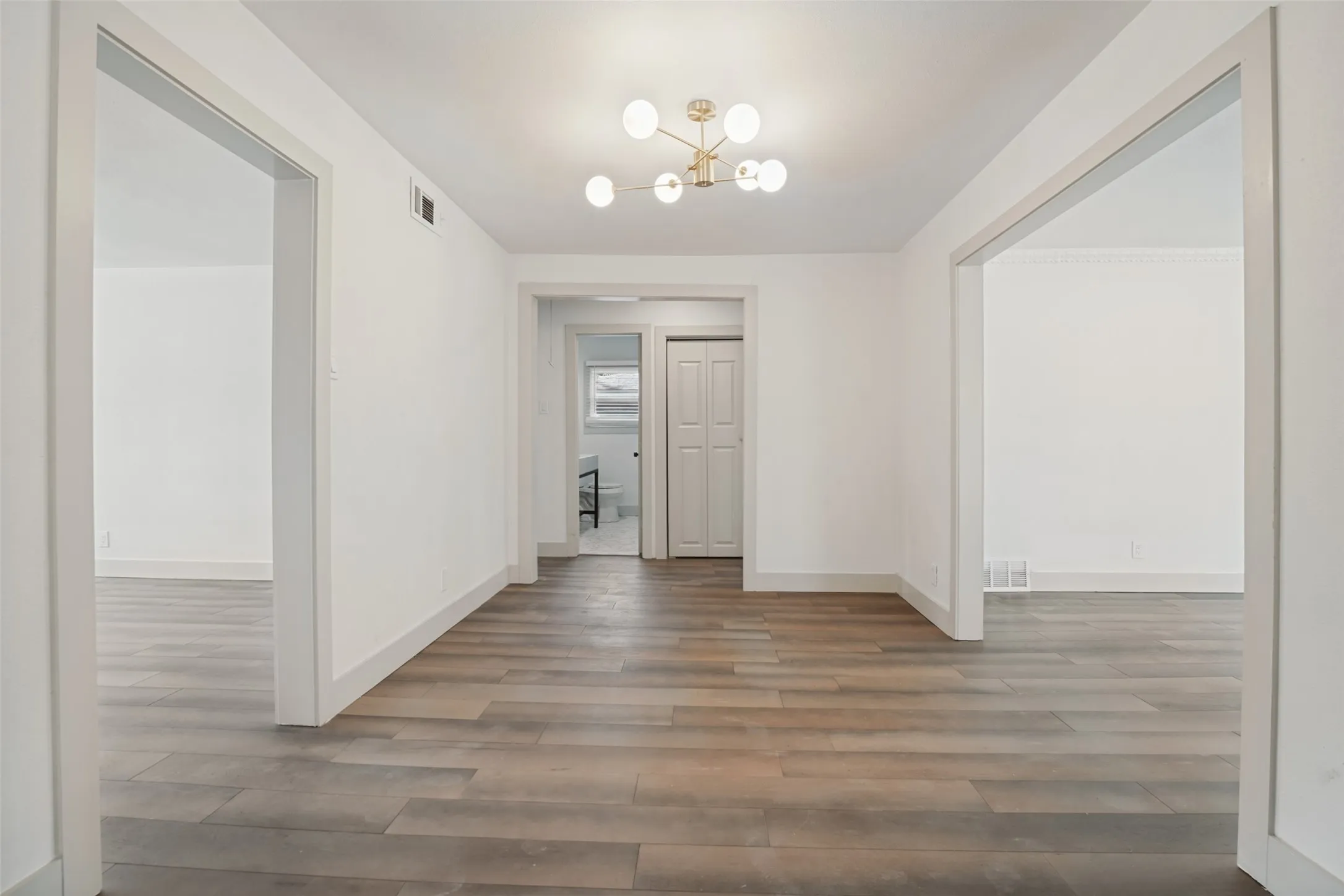 Wood-finish flooring, white walls, modern ceiling light fixture, and white trim