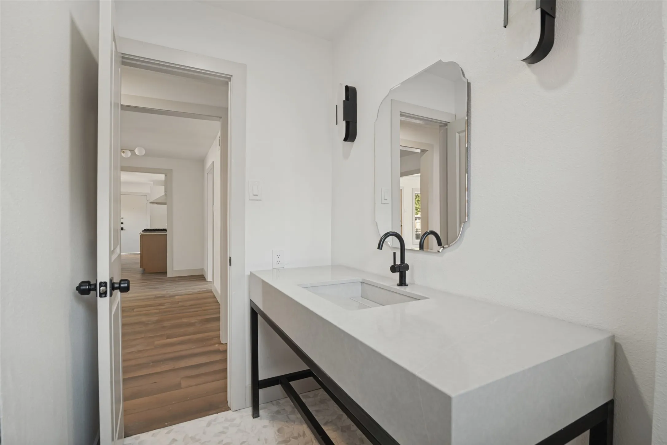 Modern floating vanity with a rectangular basin, matte black faucet, and organic-shaped wall mirror
