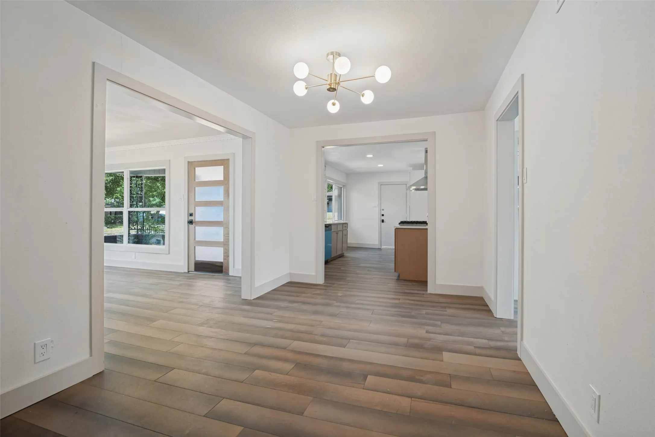 Open concept living space featuring wood-finish flooring, a modern ceiling light fixture, and multiple large window installations