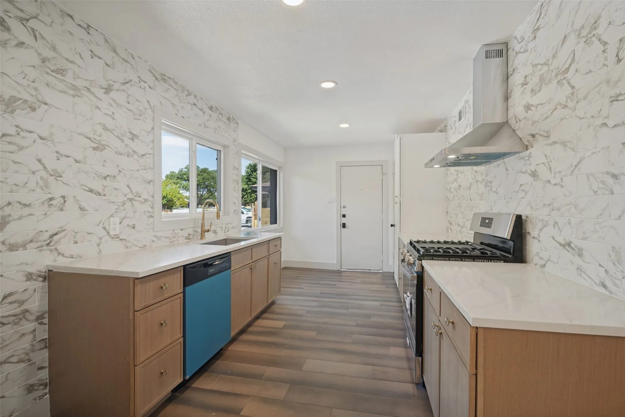 Kitchen featuring wood-finish flooring, light-toned cabinetry, white countertops, and a white tile backsplash