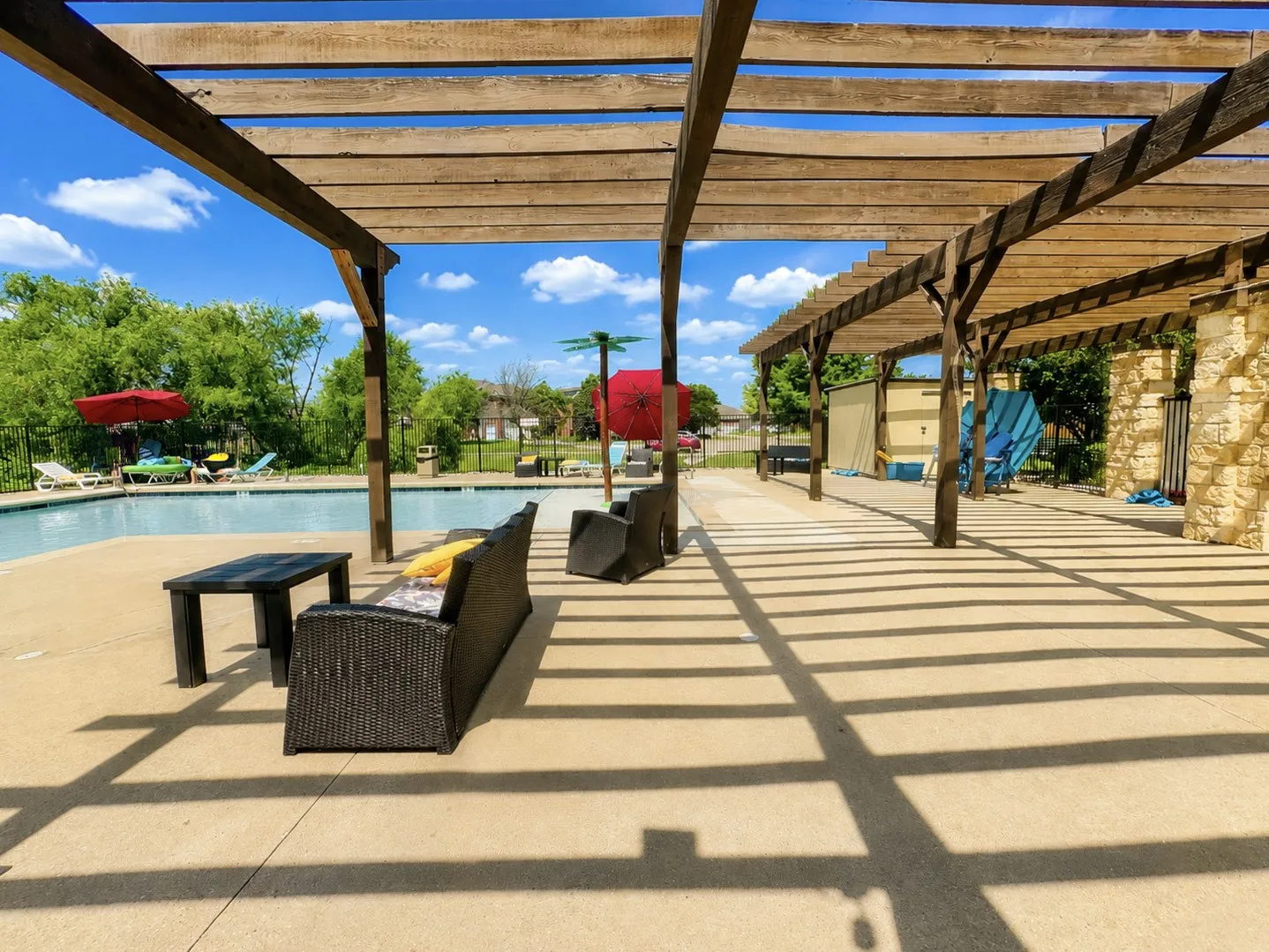 Pergola-covered patio featuring concrete decking and a stone-faced structure