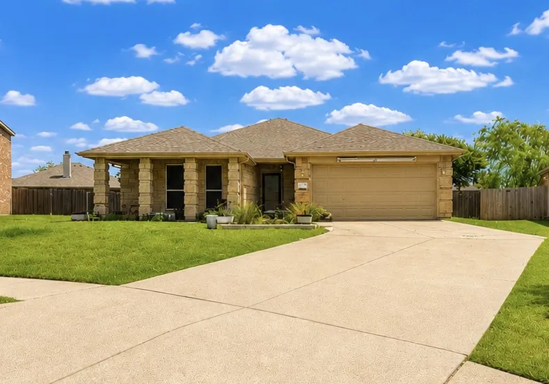 Stone facade with a covered entry, attached two-car garage, and a concrete driveway