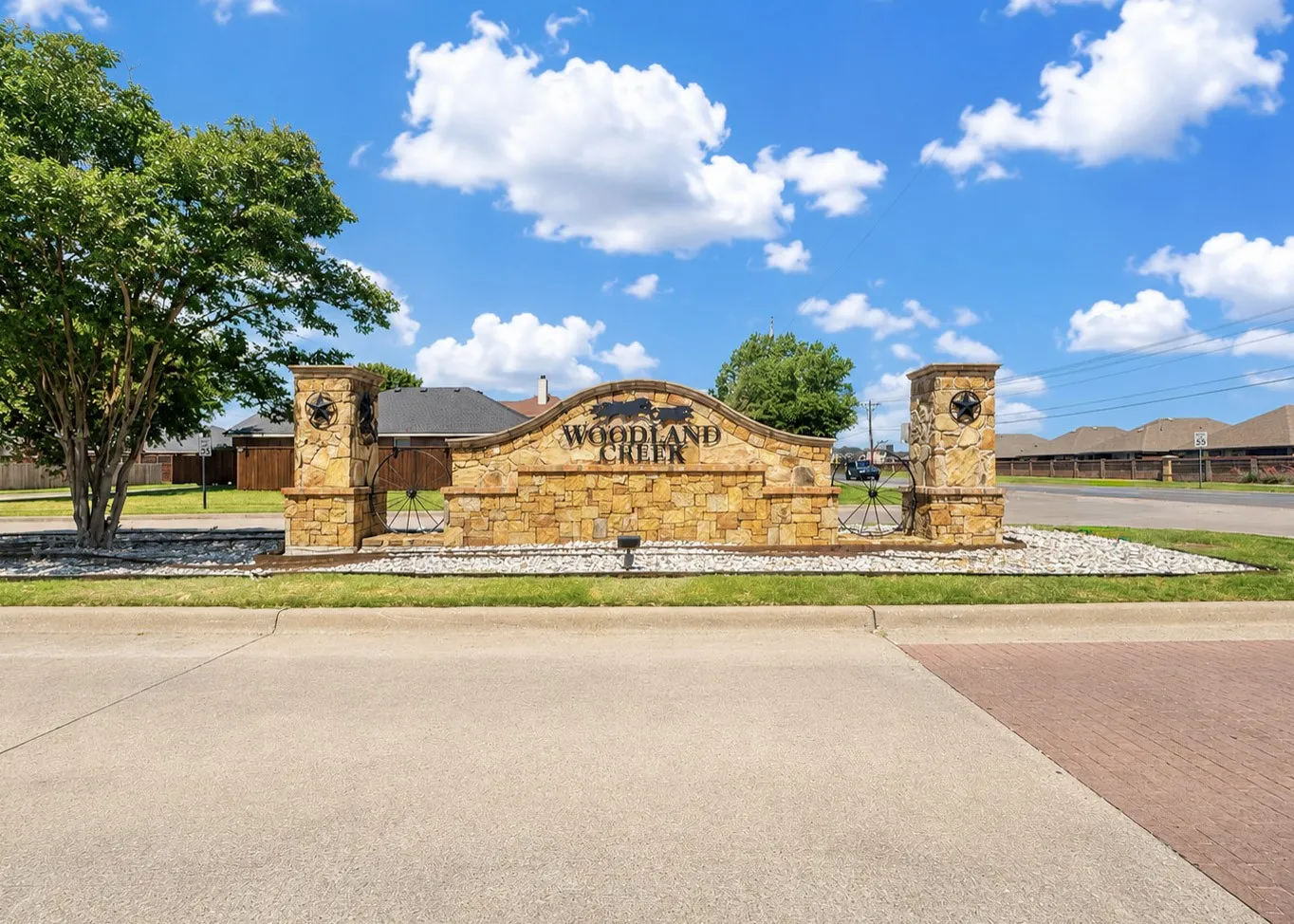 Stone entry monument with decorative metalwork and landscaping