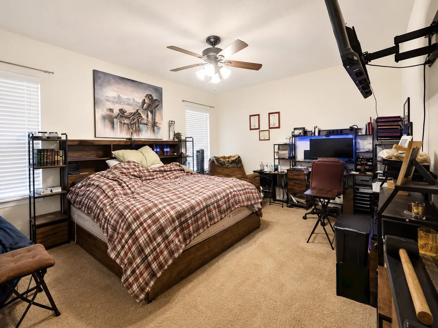Carpeted room featuring a ceiling fan, dual windows with blinds, and built-in shelving