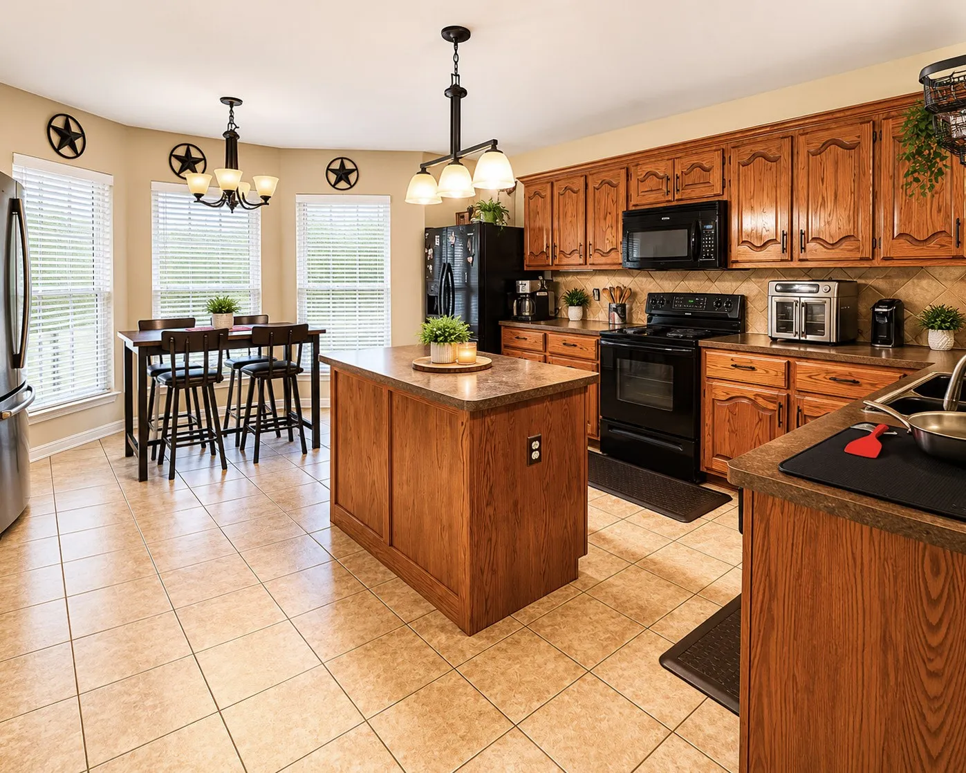 Kitchen featuring a central island with a countertop, tiled flooring, wood-finish cabinetry, and black appliances