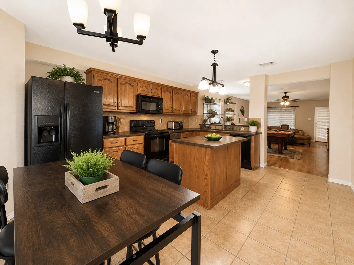 Kitchen with wood-finish cabinetry, black appliances, a central island, and ceramic tile flooring