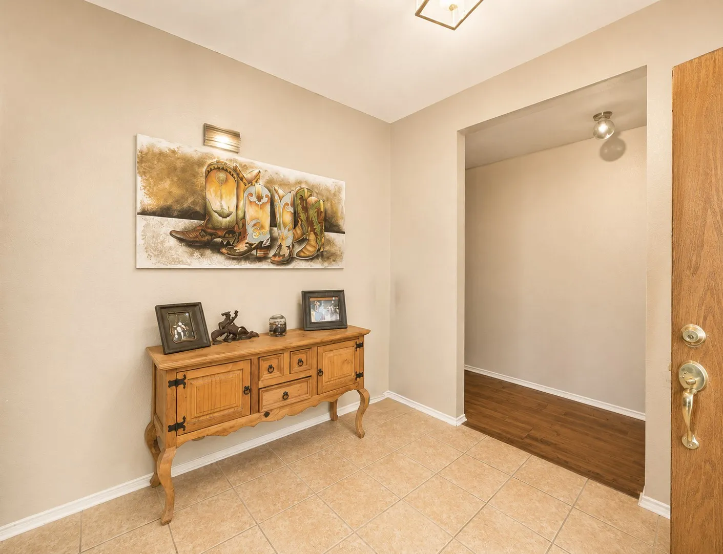 Tiled flooring entryway with a flush-mount ceiling light and recessed wall niche with a spotlight
