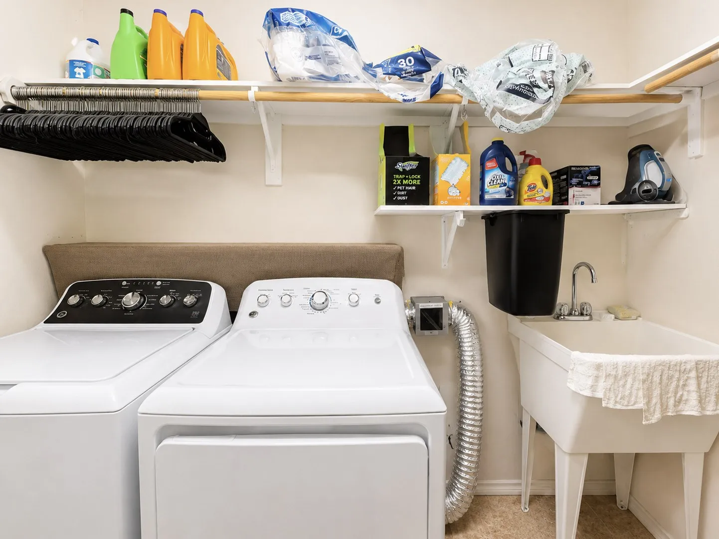 Dedicated laundry space featuring a utility sink, wall-mounted shelving, and a hanging rod