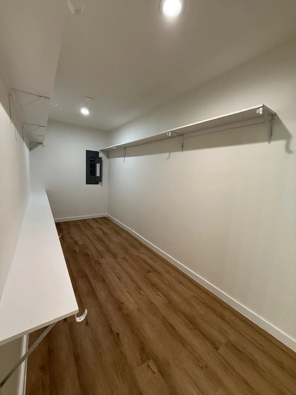 Recessed lighting, wood-finish flooring, white walls, built-in shelving, and a built-in folding table