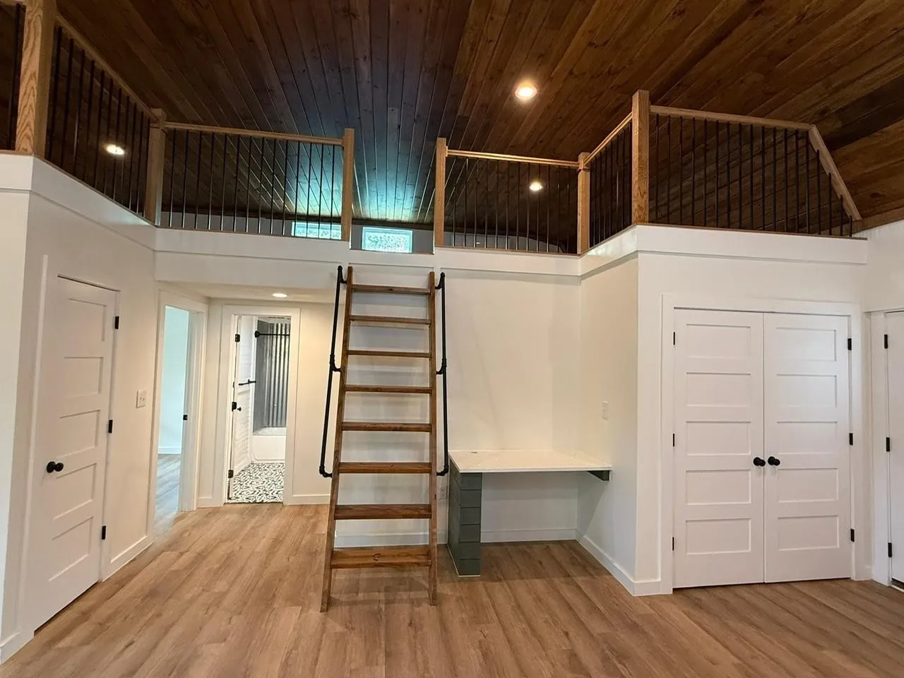 Wood-finish flooring, wood plank ceiling, built-in desk, built-in ladder, and white paneled doors