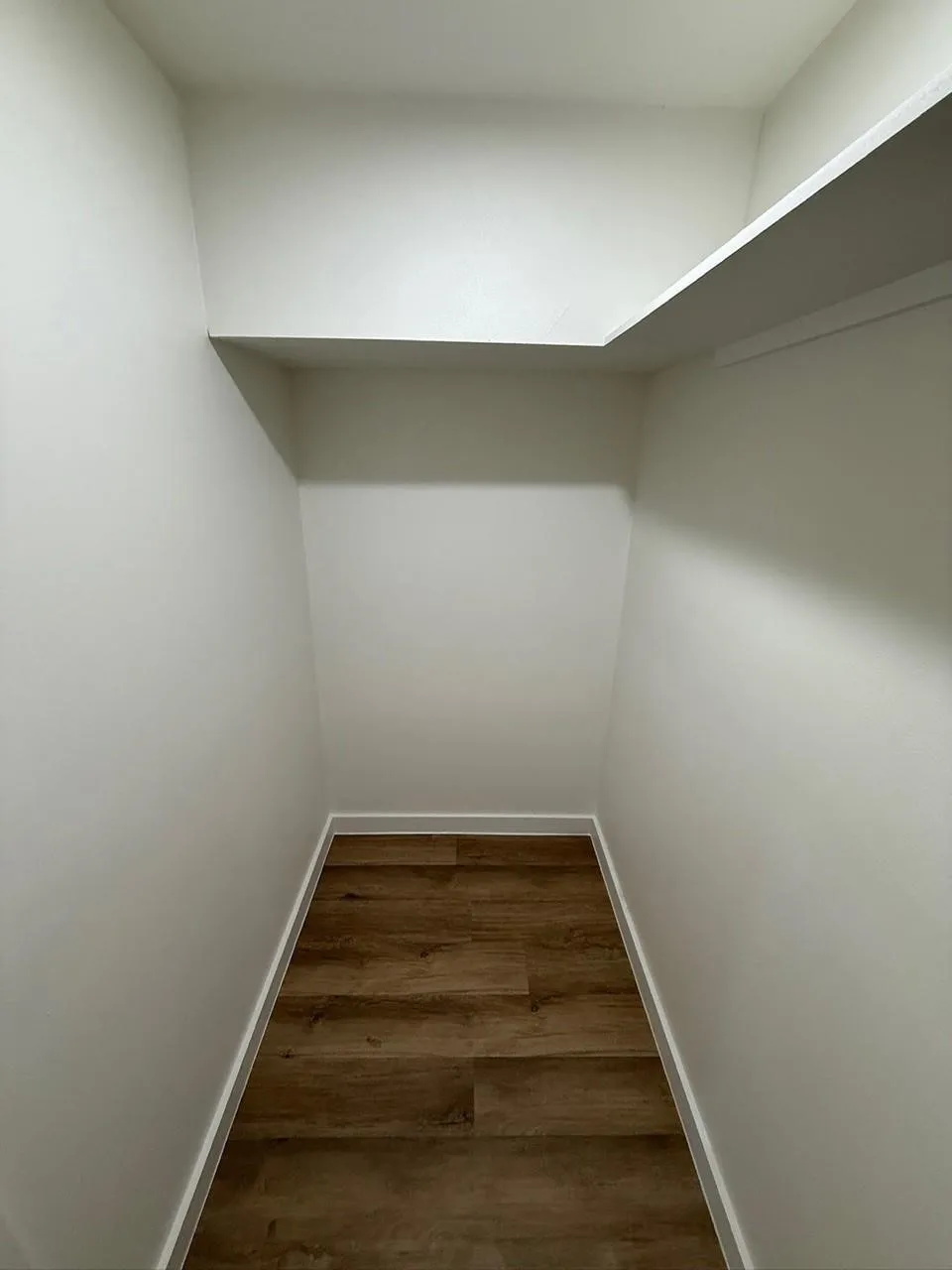 Wall-to-wall wood-finish flooring with crisp white baseboards and painted walls