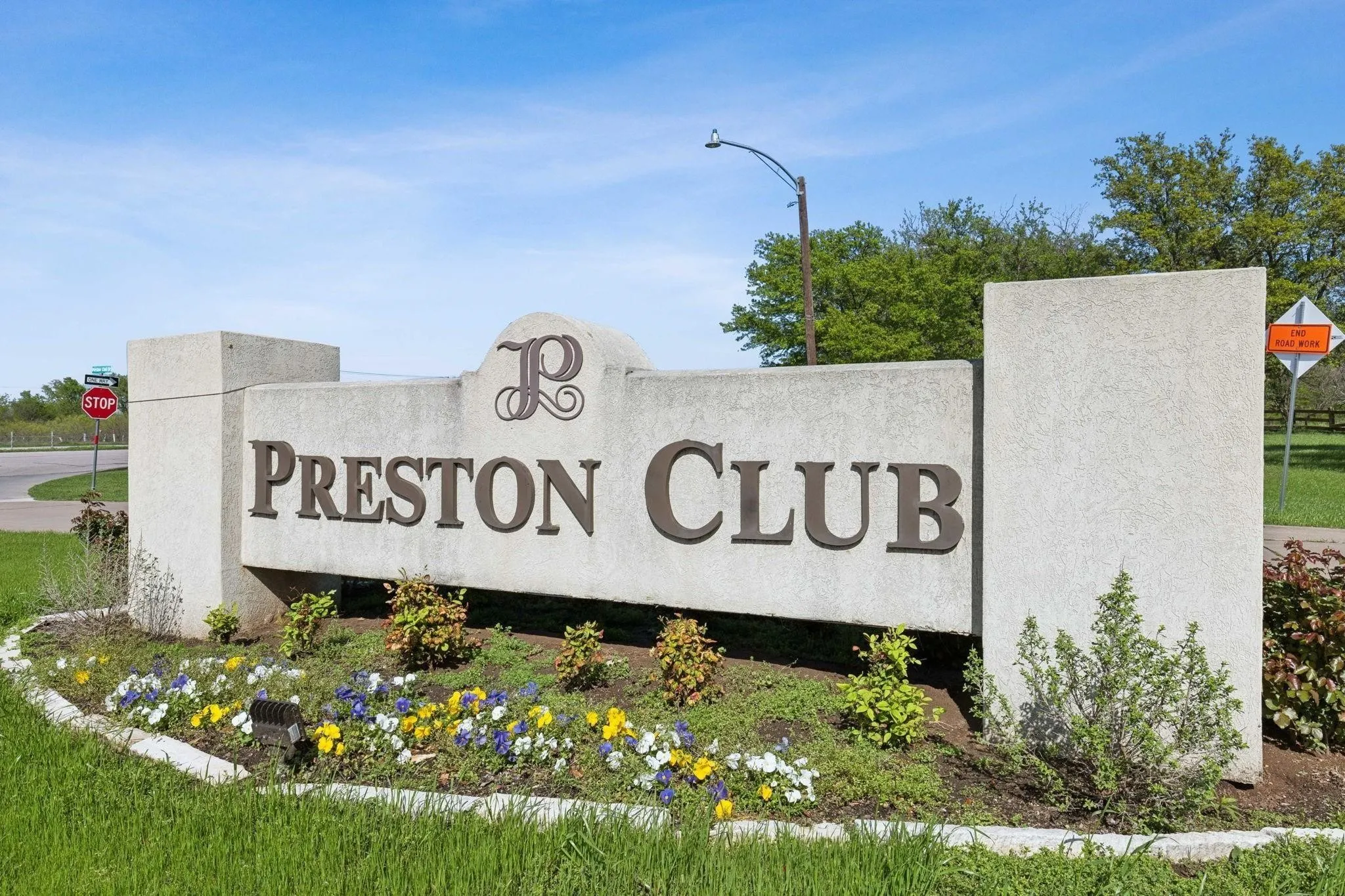Preston Club entrance sign featuring stone construction, integrated landscaping, and a manicured lawn
