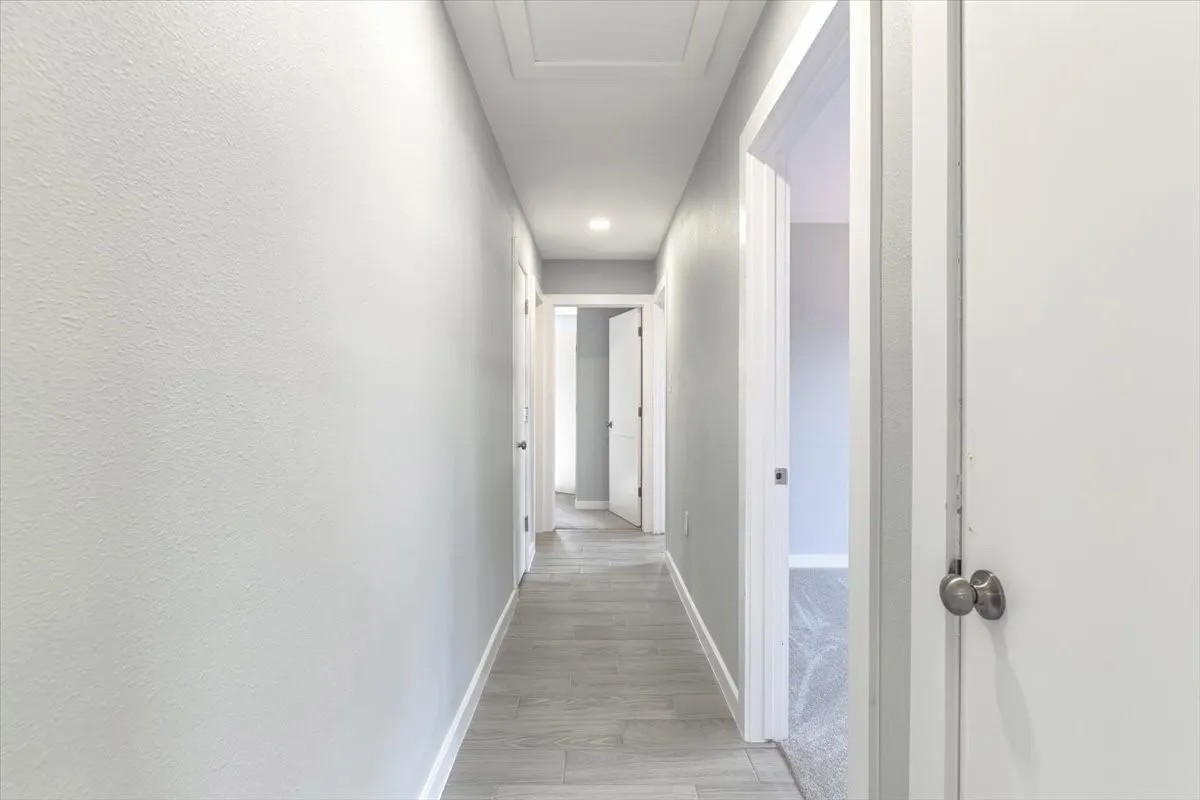 Hallway featuring light grey tile flooring and recessed lighting