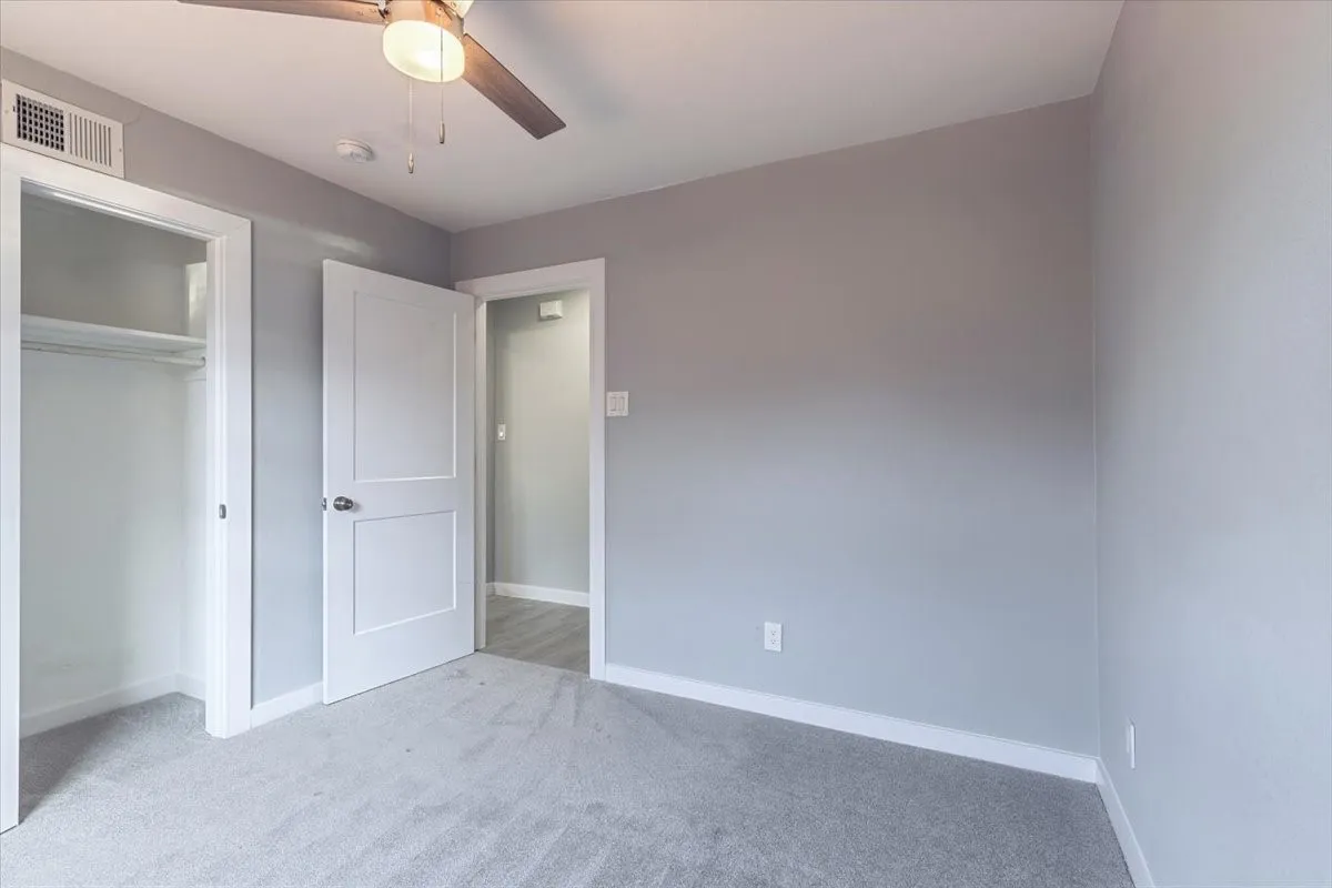 Gray carpet white trim, and a ceiling fan with integrated lighting