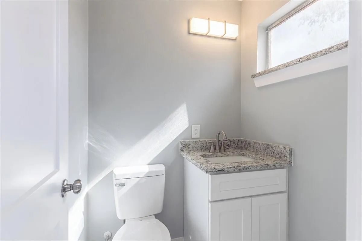 Vanity with a granite countertop, undermount sink, and brushed nickel faucet