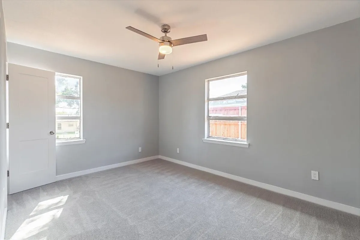Recessed lighting, ceiling fan with integrated light, two windows, and gray carpeting