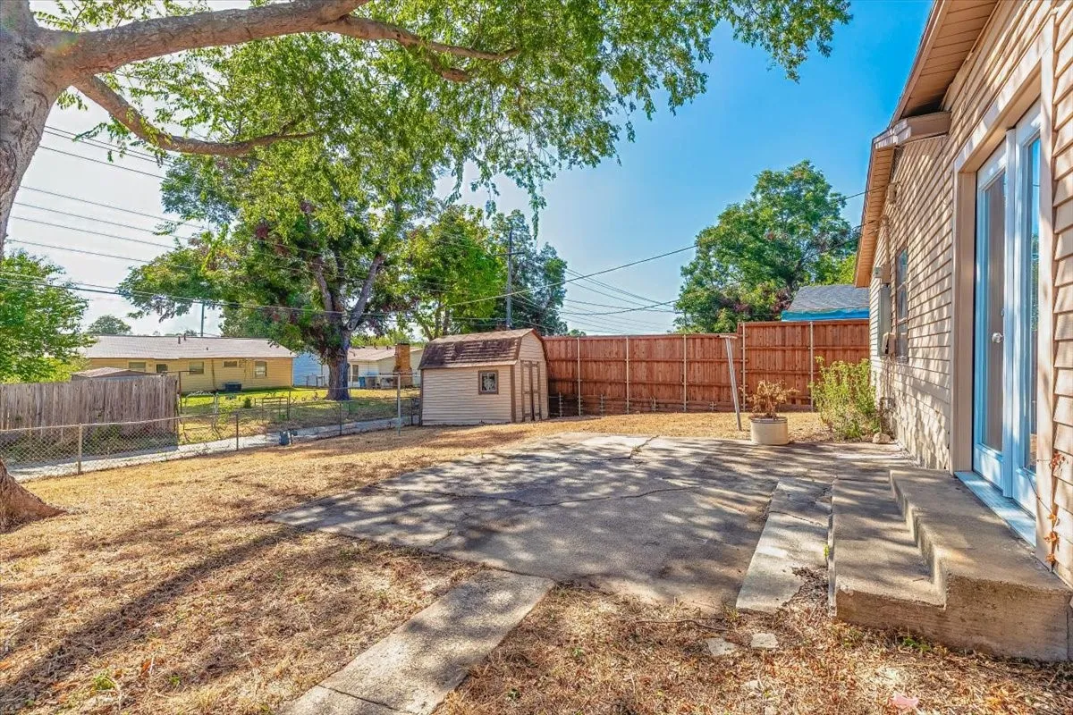 Expansive outdoor space featuring a paved patio, a storage shed, and a privacy fence