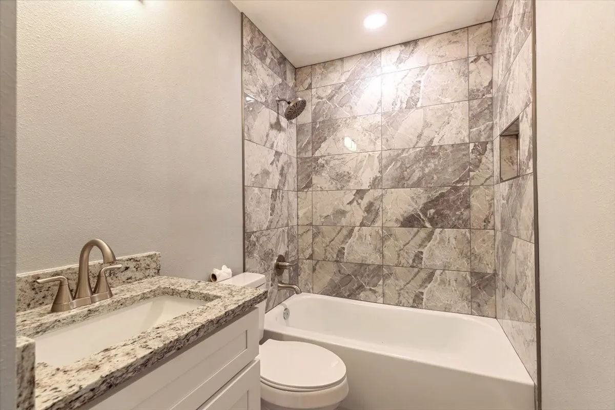 Bathroom featuring a white vanity with a light granite countertop, an undermount sink, and brushed nickel fixtures