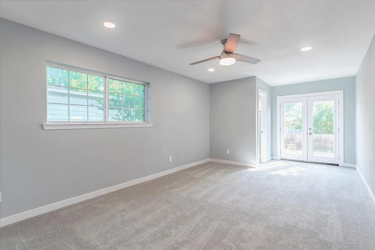 Recessed ceiling lighting, ceiling fan with integrated light, light gray tile double French doors, and a large window