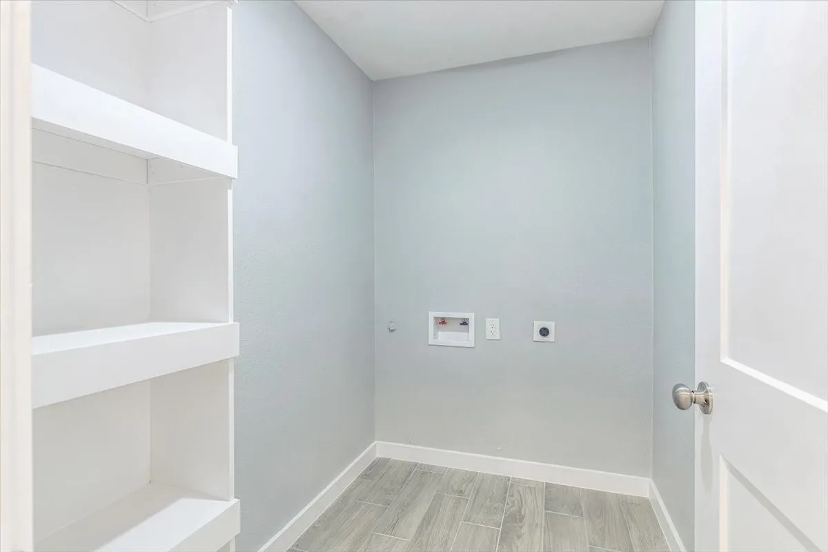 Built-in shelving, light gray wall finish, wood-finish flooring, white door, and brushed nickel hardware