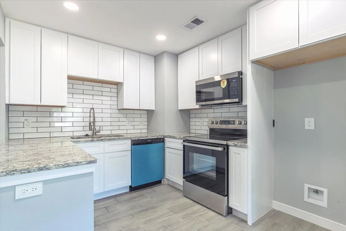 White shaker cabinetry, light-toned granite countertops, a subway tile backsplash, and stainless steel appliances