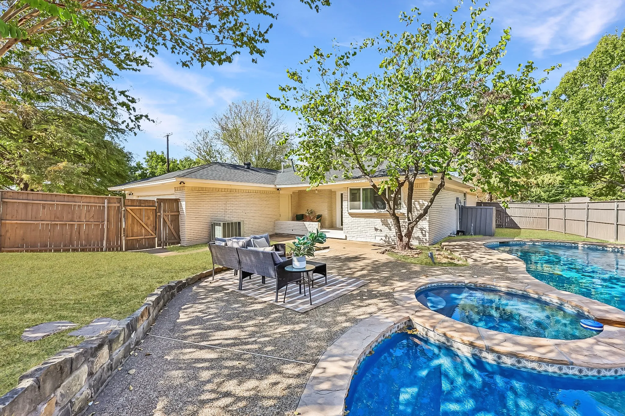 Kidney-shaped swimming pool with an integrated spa, stone coping, and a surrounding stone patio