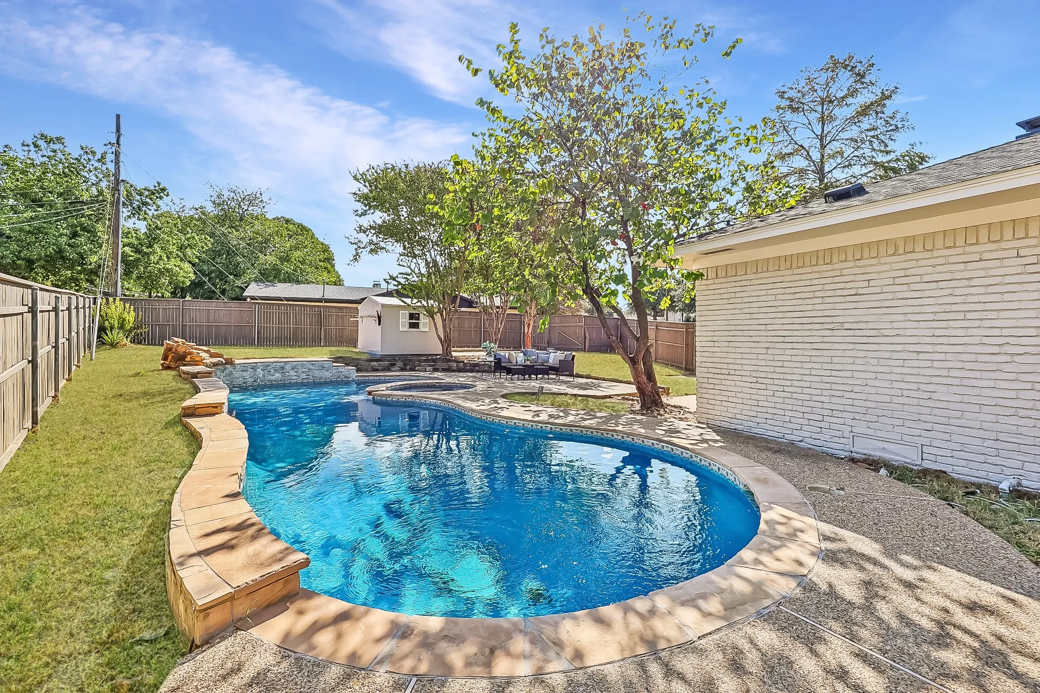Freeform swimming pool with stone coping, separate spa, and rock waterfall feature