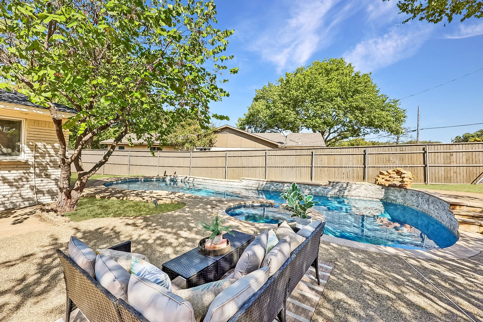 Backyard featuring a custom-shaped swimming pool with stone and tile accents