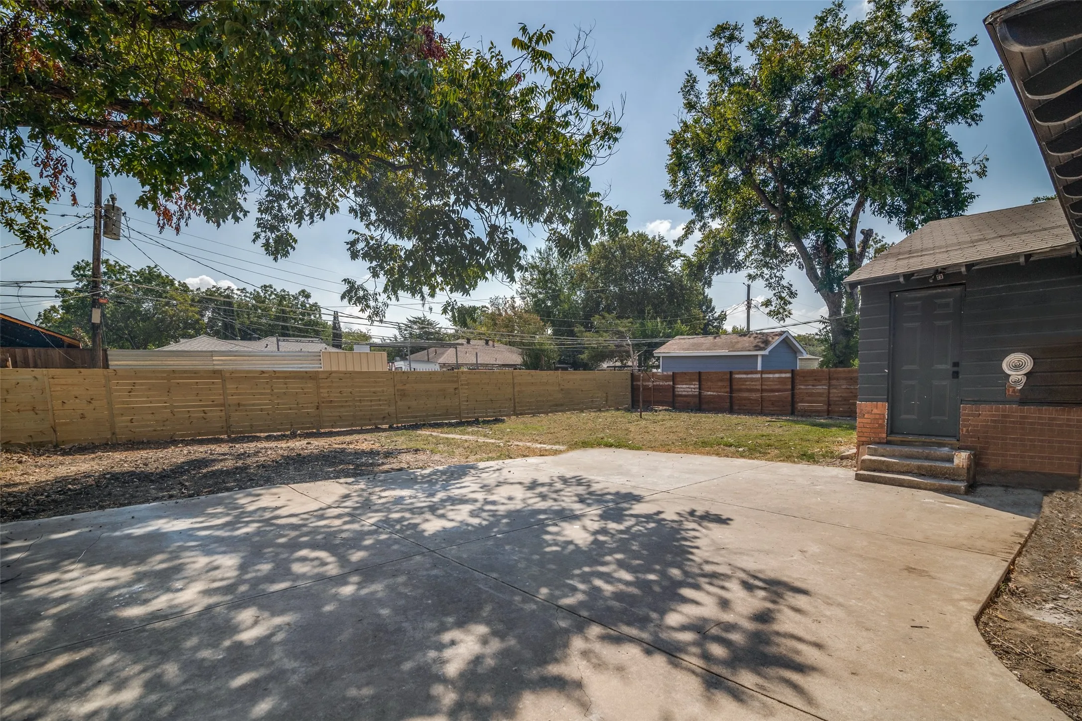 Expansive concrete patio with a new wood privacy fence