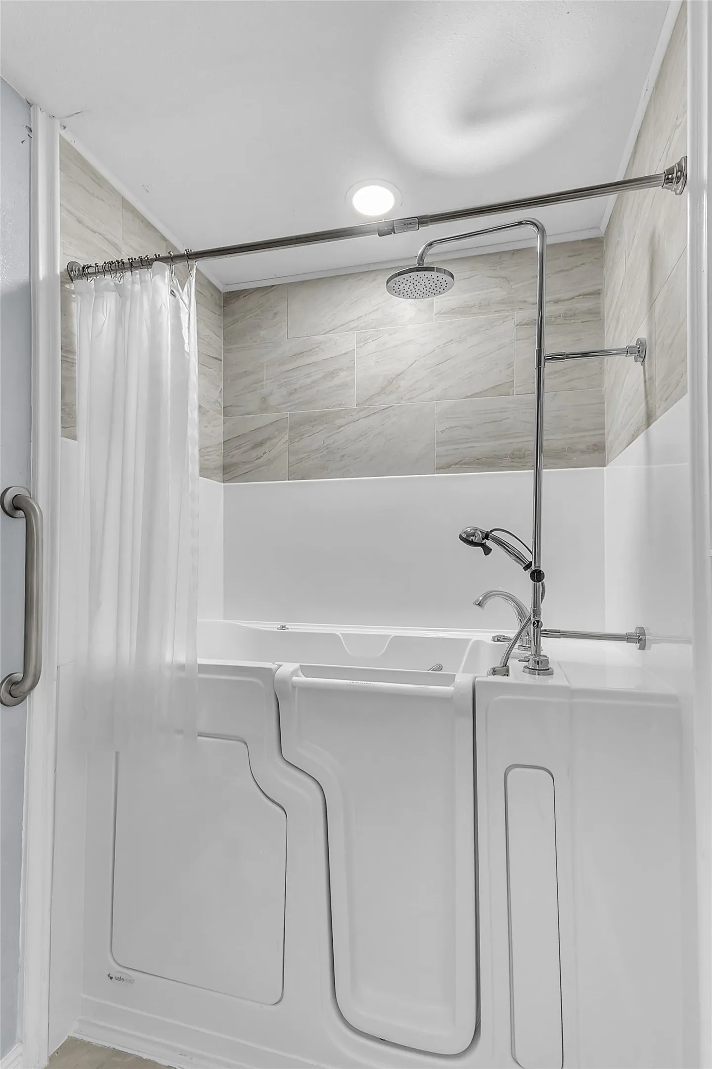 Walk-in shower with sliding glass doors, equipped with a rainfall showerhead and chrome fixtures, featuring beige tile accent walls and a built-in tub.