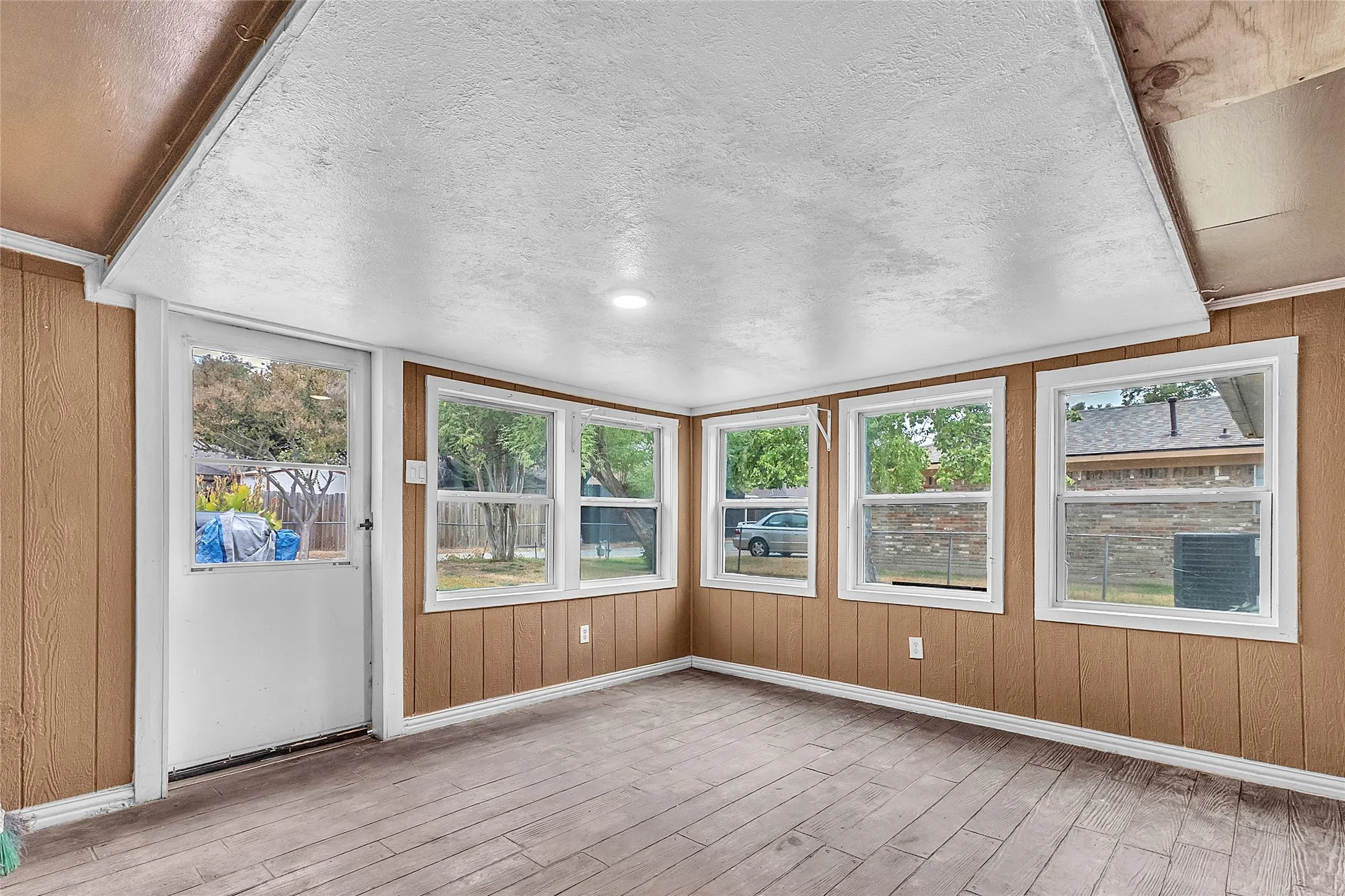 Sunroom with large windows, recessed lighting, and hardwood flooring, showcasing an open layout and abundant natural light.