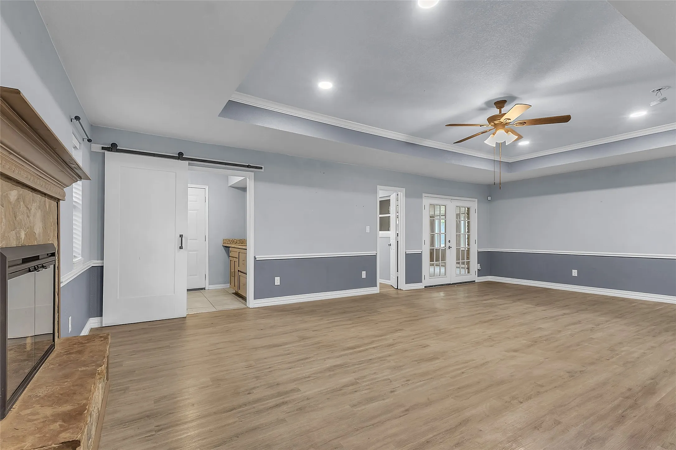 Living room with hardwood flooring, vaulted ceiling, recessed lighting, and an open layout leading to the kitchen and dining areas.