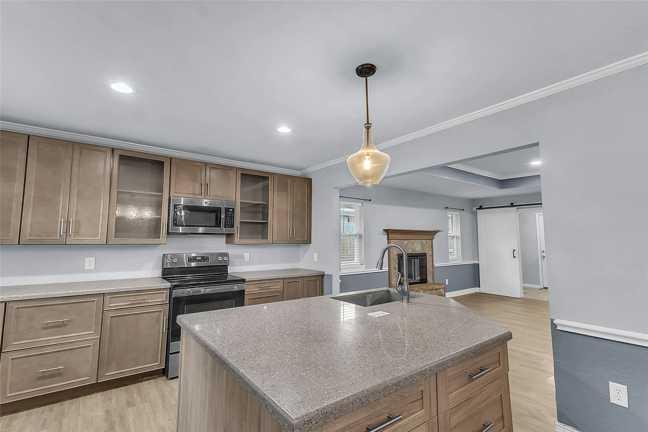 Open-plan kitchen with stainless steel appliances, recessed lighting, quartz countertops, and a central island in a light-filled layout