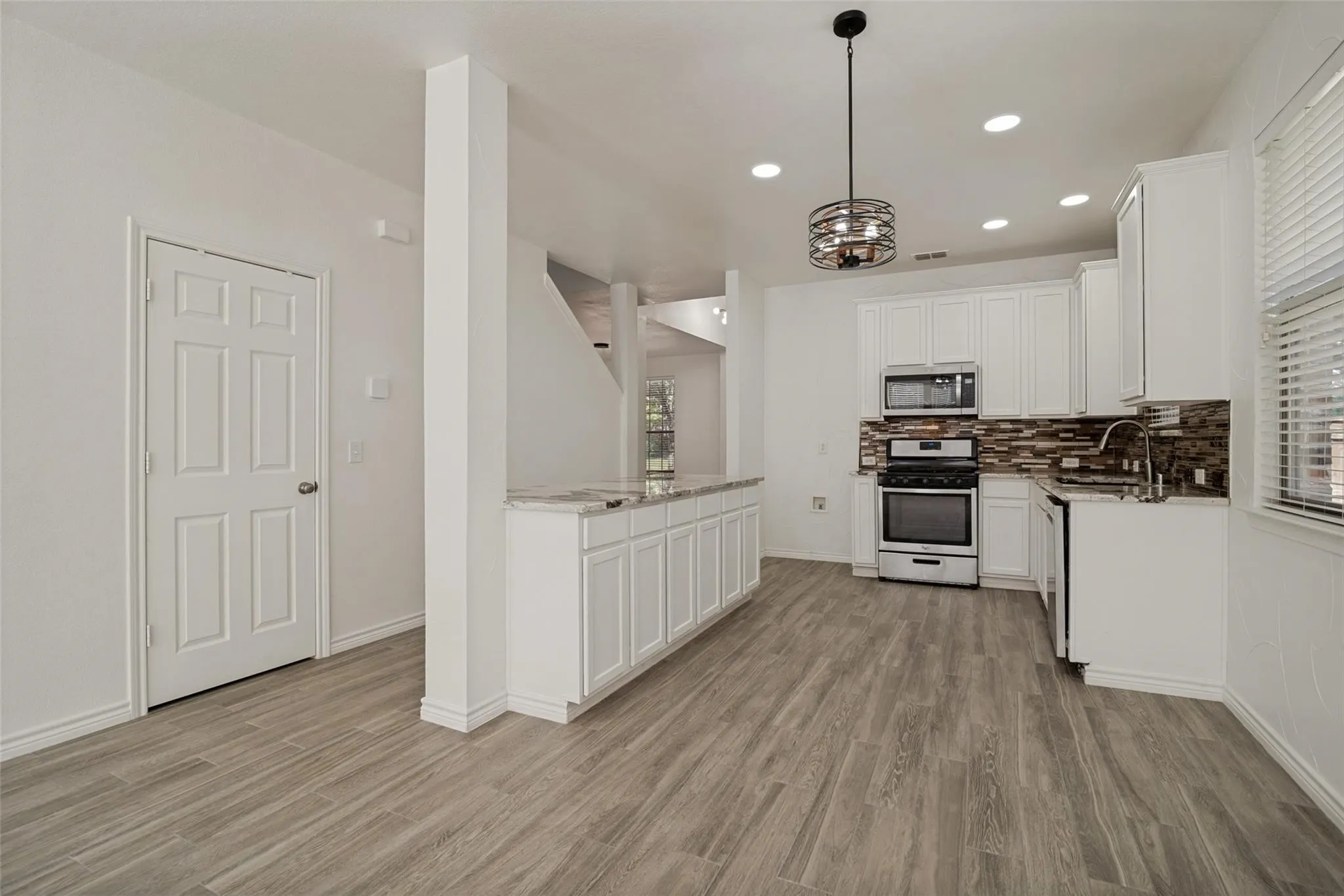 Contemporary kitchen featuring stainless steel appliances, white cabinetry, and a mosaic tile backsplash