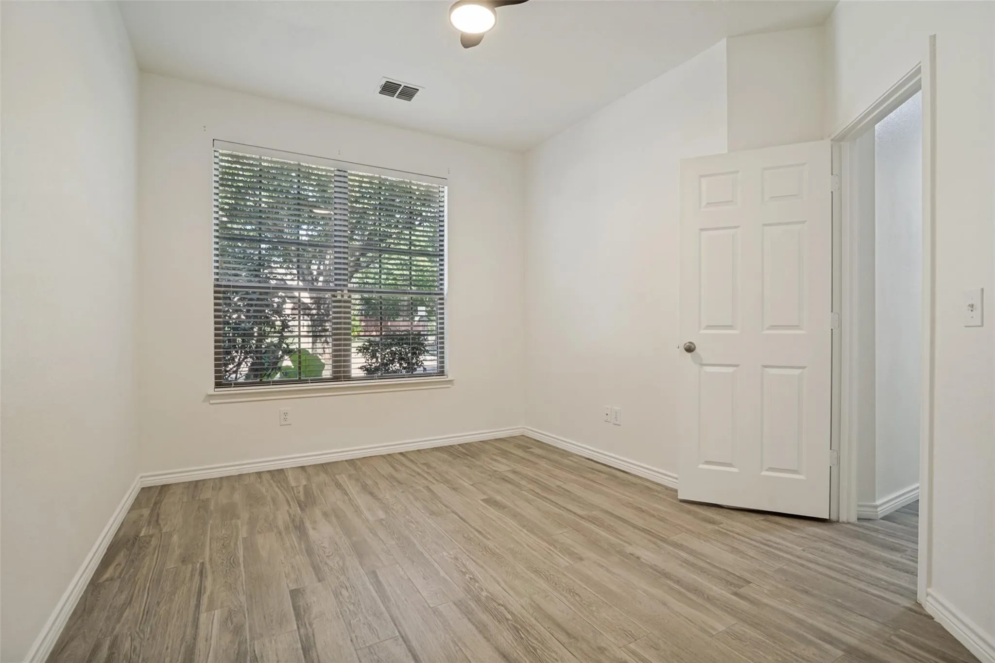 Wood-finish flooring, white paneled door, and a window with blinds