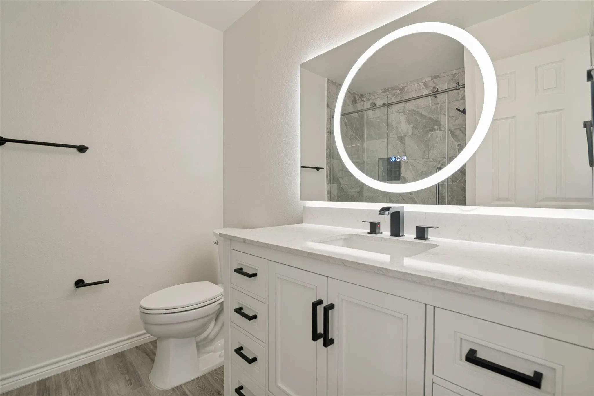 White vanity cabinetry with matte black hardware, integrated sink, and quartz countertop