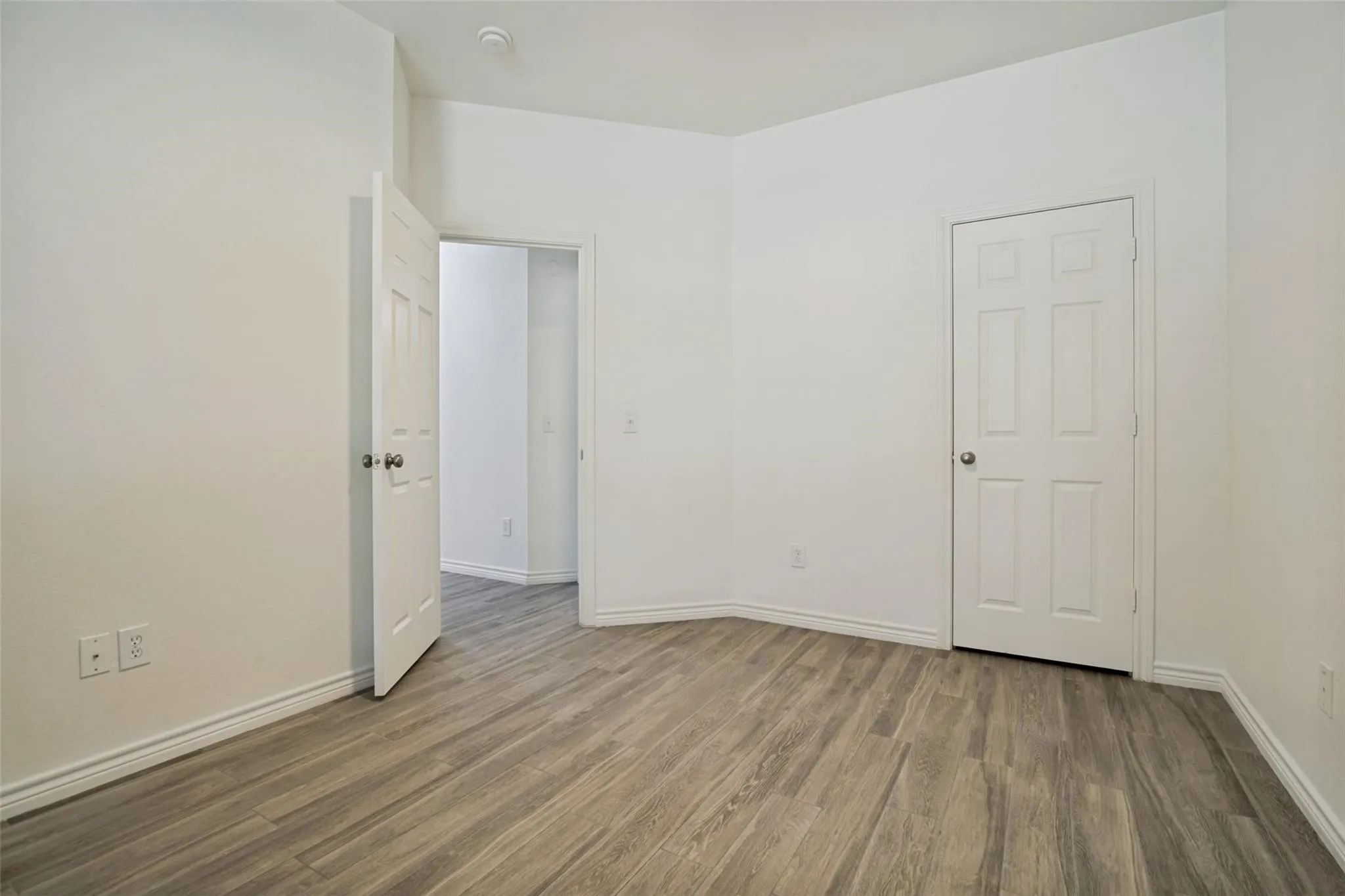Wood-finish flooring, white paneled doors, and white walls