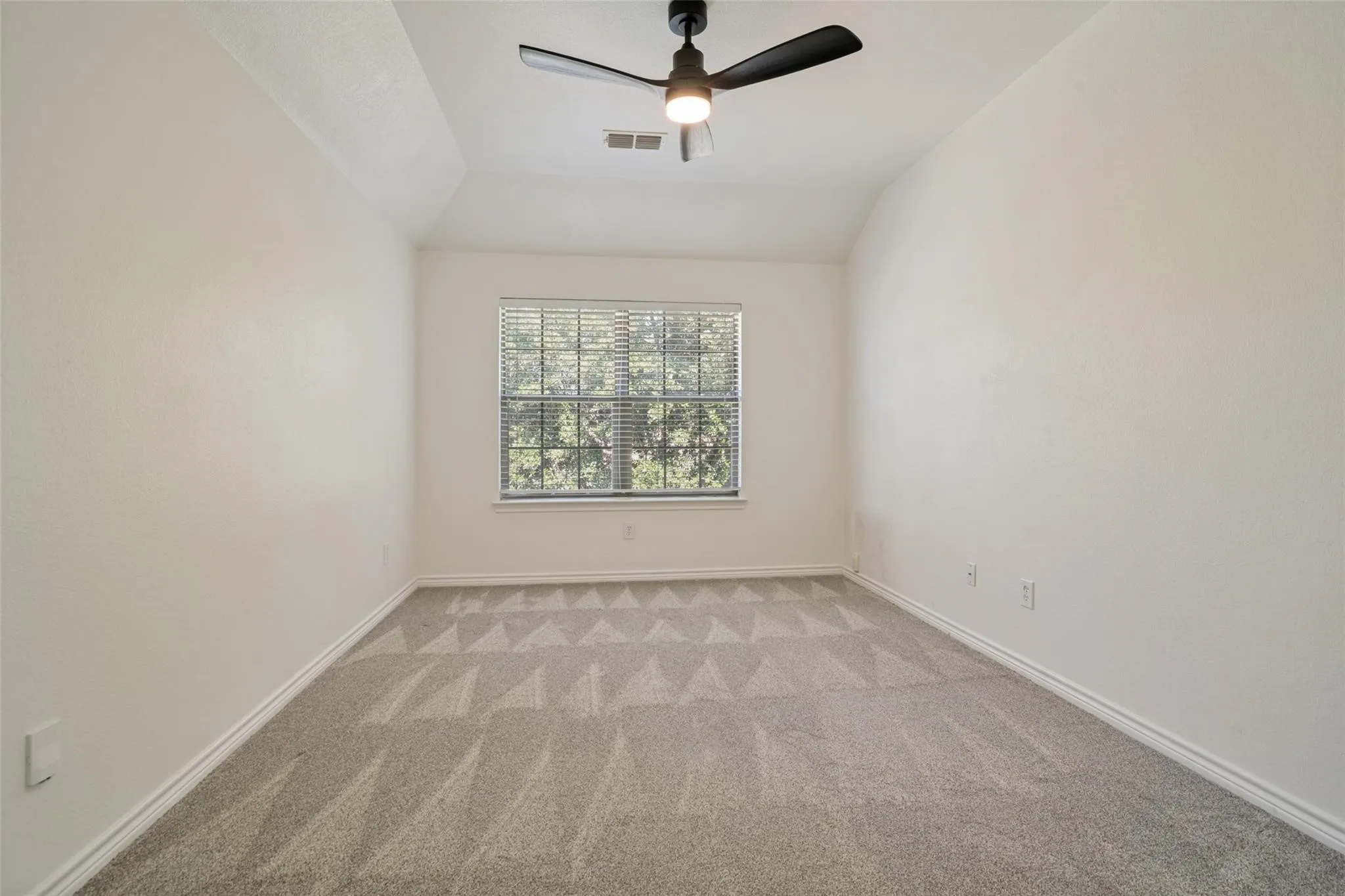 Vaulted ceiling with a ceiling fan, carpet flooring, and a window with blinds