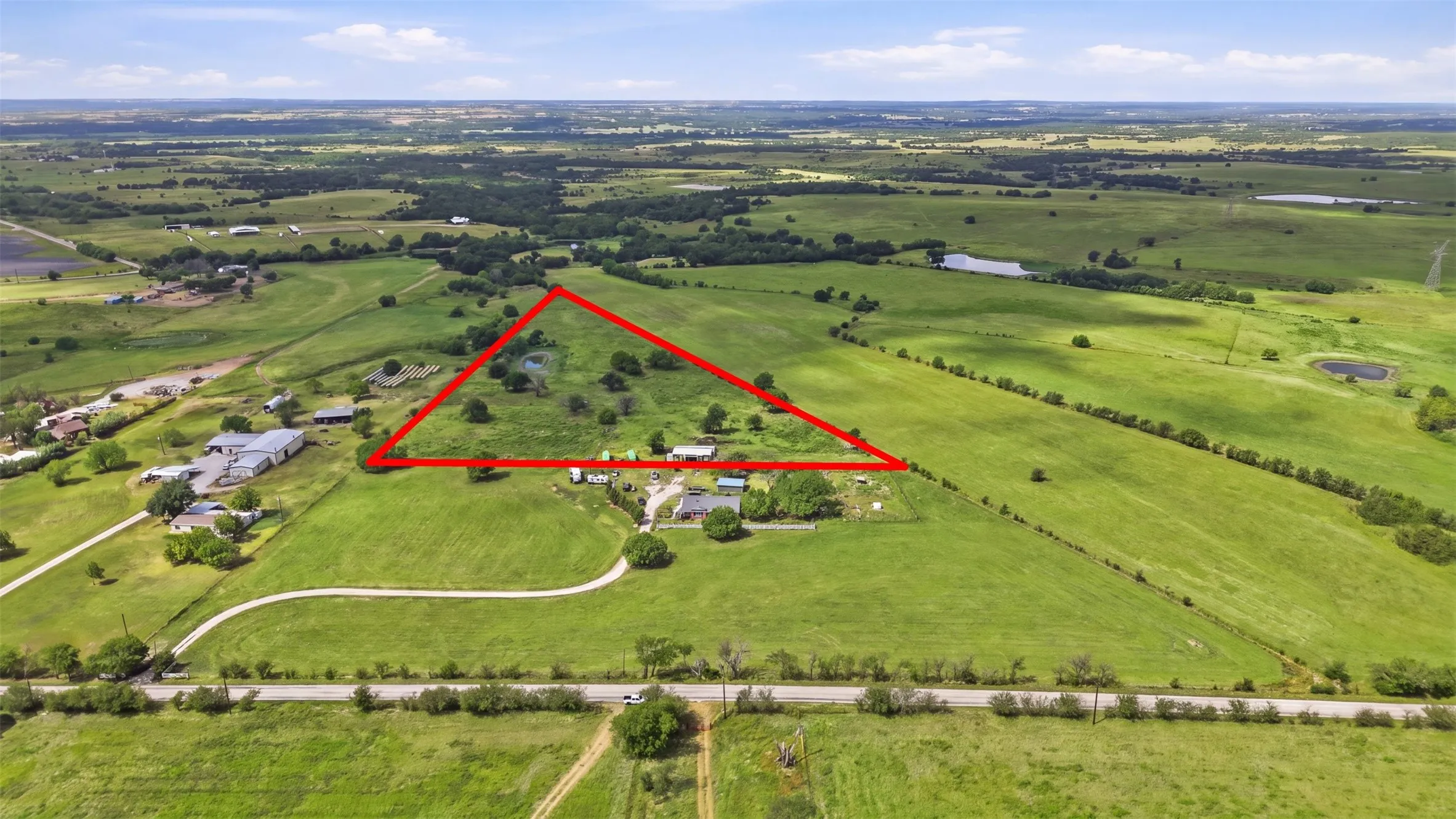 Expansive acreage featuring multiple buildings, a pond, and mature trees