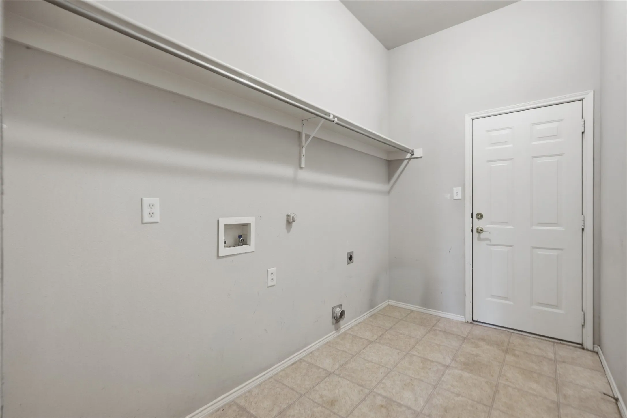Utility room with tile flooring, wall-mounted shelving, and a paneled entry door