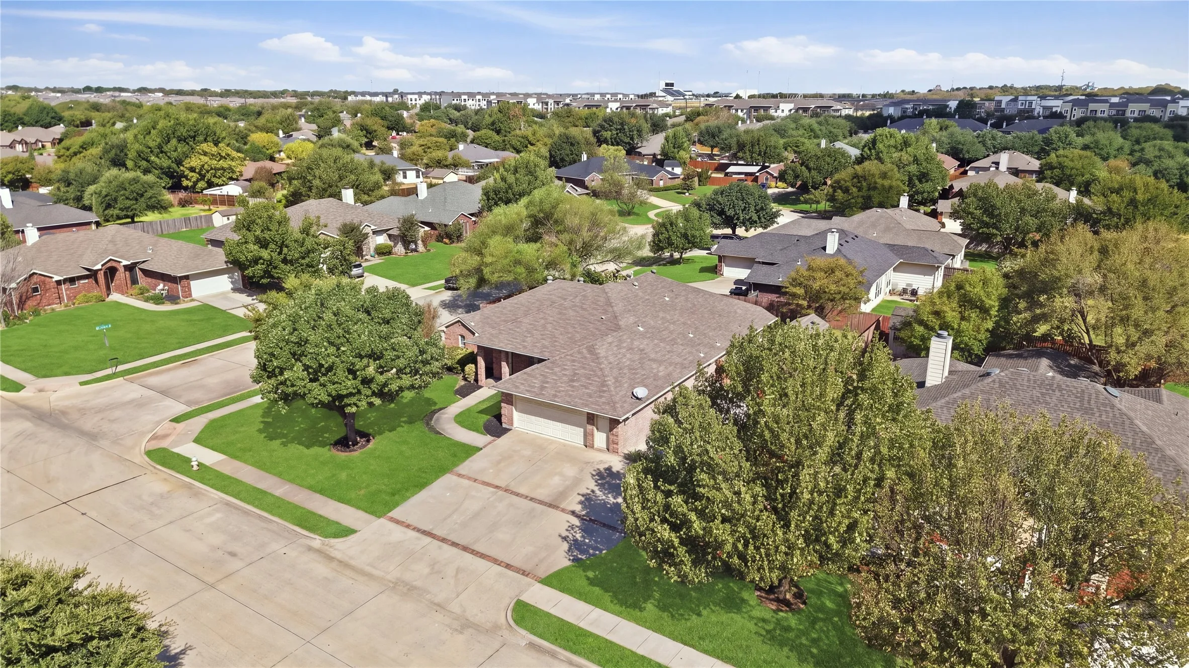 Residential property featuring a brick exterior, attached two-car garage, and a lush green lawn